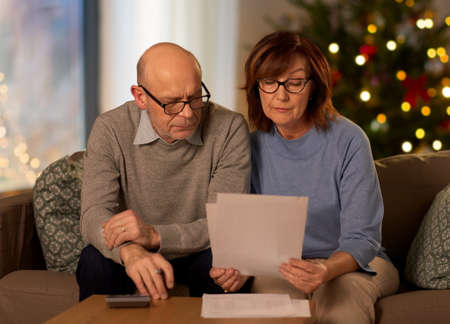 senior couple with bills at home on christmasの写真素材