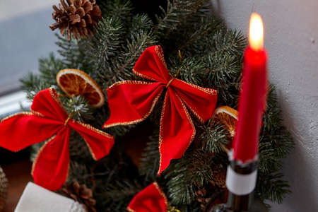 christmas wreath with red bows and burning candleの写真素材