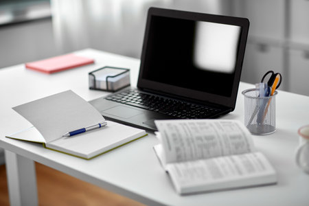laptop, notebook and book on table at home officeの写真素材
