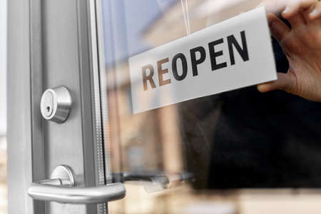 close up of woman hanging reopen banner on door