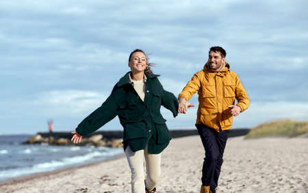 couple running along autumn beachの写真素材
