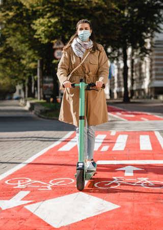 woman riding scooter along bike lane road in city