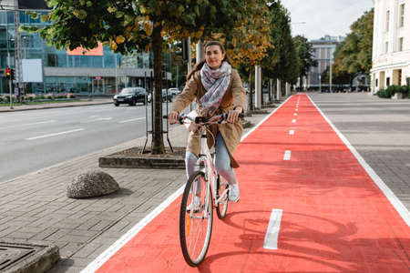 woman riding bicycle along red bike lane in cityの写真素材