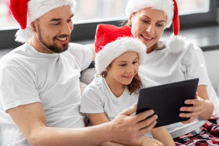 happy family with tablet pc in bed on christmasの写真素材