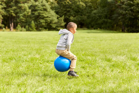 happy little boy bouncing on hopper balls at parkの写真素材