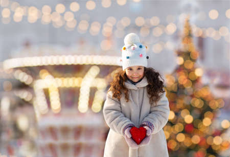 happy little girl with heart over christmas lightsの写真素材