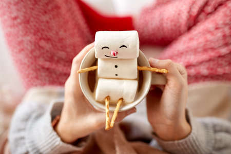 hands with marshmallow snowman in mug on christmasの写真素材