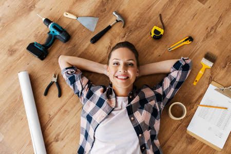 woman with working tools lying on wooden floorの写真素材