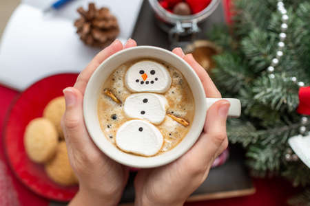 hands with marshmallow snowman in mug on christmasの写真素材