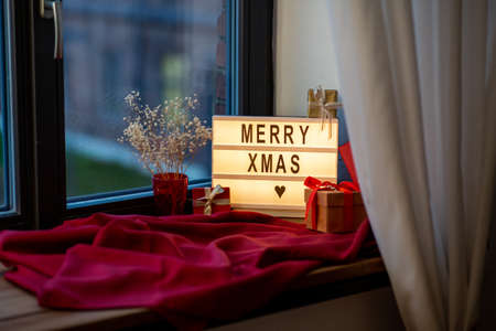 holidays, decoration and celebration concept - merry christmas greeting on light box and gift boxes...