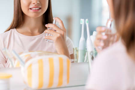 teenage girl spraying perfume at bathroom