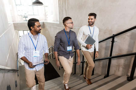 men with conference badges walking upstairs