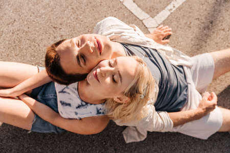 happy couple sitting on basketball playground