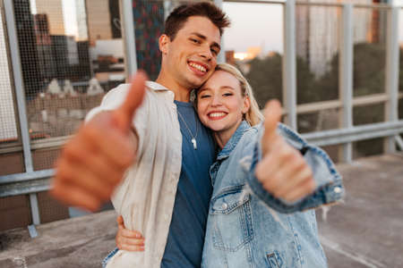 happy young couple showing thumbs up on roof topの写真素材