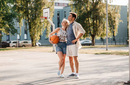 happy couple with ball on basketball playgroundの写真素材