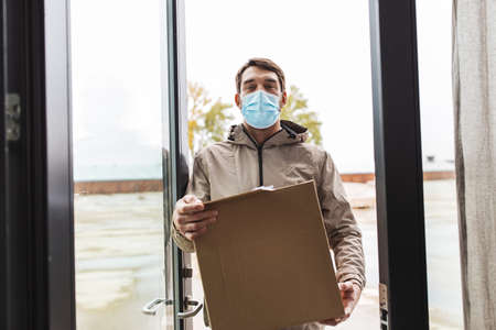 delivery man in face mask holding parcel boxの写真素材