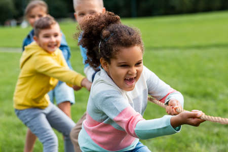 happy children playing tug-of-war game at park