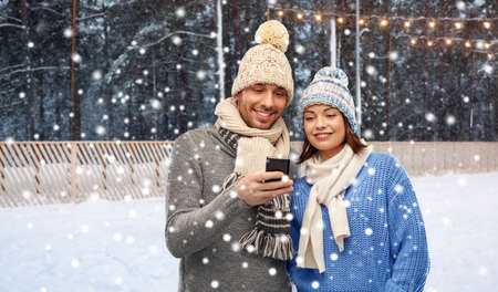 happy couple in winter clothes with smartphoneの写真素材