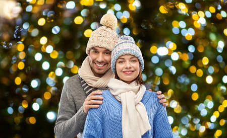 happy couple in winter clothes christmas lightsの写真素材