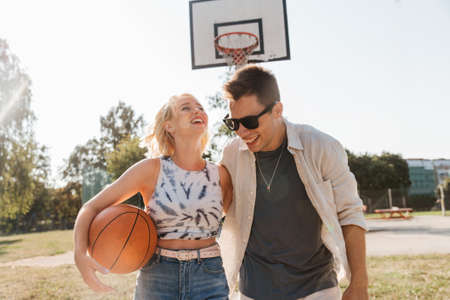 happy couple with ball on basketball playgroundの写真素材