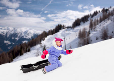 little girl with sled on snow hill in winterの写真素材