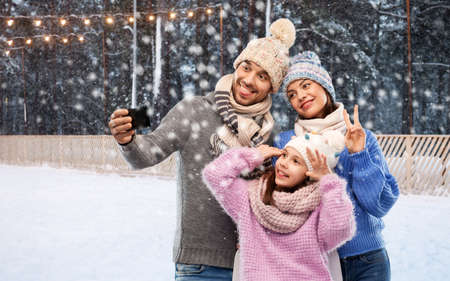 family taking selfie with smartphone at ice rinkの写真素材
