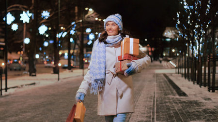 happy woman with christmas gifts walking in winterの写真素材