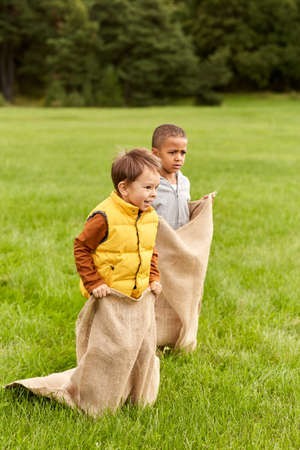 happy boys playing bag jumping game at parkの写真素材