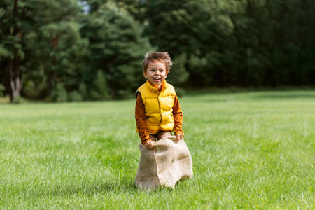 happy boy playing bag jumping game at parkの写真素材