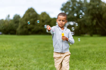 little boy playing with soap bubbles at park