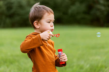 little boy playing with soap bubbles at park