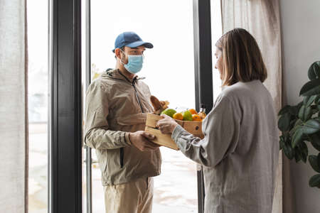 food delivery man in mask giving order to customer