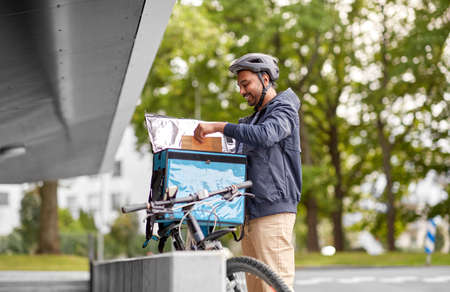 indian delivery man with bag and bicycle in city