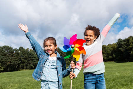 happy girls with pinwheel having fun at parkの写真素材