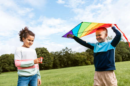 happy boy and girl with kite playing at parkの写真素材