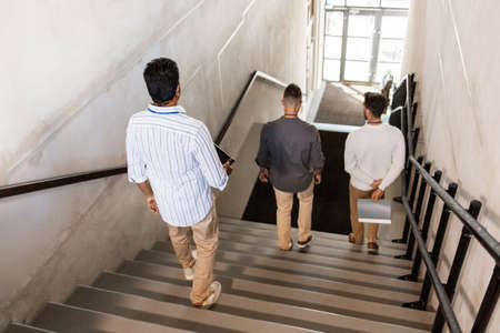 men walking down office stairs and talkingの写真素材