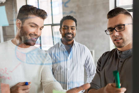 men working at office with charts on glass boardの写真素材