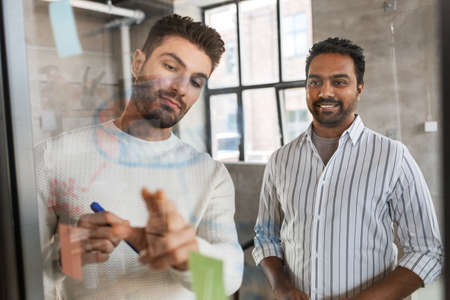 men working at office with charts on glass boardの写真素材