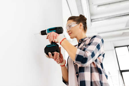 woman with perforator drilling wall at homeの写真素材