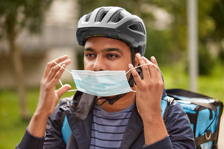 food delivery man in mask and bicycle helmet