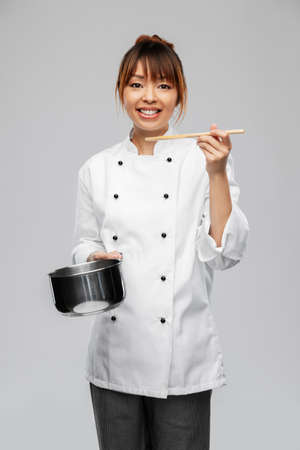 female chef with saucepan tasting foodの写真素材