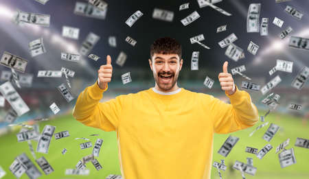 happy man over money rain on football fieldの写真素材