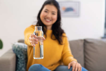 close up of woman with bottle of water at home