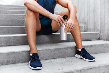 tired sportsman with bottle sitting on stairs