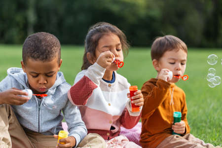group of children blowing soap bubbles at parkの写真素材