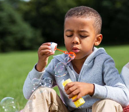 little boy blowing soap bubbles at parkの写真素材