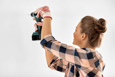 woman with perforator drilling wall at home