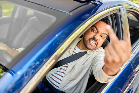 angry man driving car and showing middle fingerの写真素材