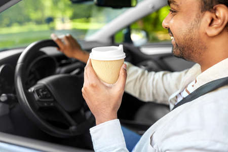 happy indian man or driver with coffee driving carの写真素材