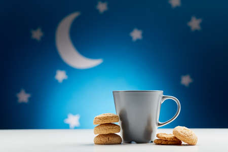 close up of coffee cup and cookies at nightの写真素材